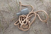 Rope and plastic bottle on sandy floor