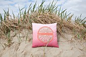 Cushion with crocheted motif on pink ombré cover on sandy bean