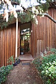 View from garden towards redwood timber house with open front door
