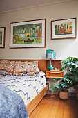 Double bed with wooden frame and bedside table integrated in retro-style headboard below collection of pictures on wall