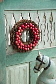 Wreath of bark and red apples hung on weathered wooden door