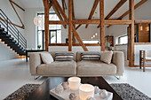 Open-plan living room with exposed wooden beams and modern furniture