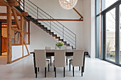 Esstisch mit Stühlen in modernem Ambiente mit Holzbalken und Treppe