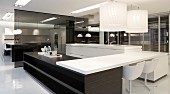 Designer kitchen with black and white elements - pendant lamps above table top mounted across wooden counters