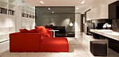 Red sofa combination and delicate side table on white flokati rug in open-plan lounge with smoked glass partition in background
