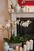 White pillar candles and white orchids in front of fireplace and on mantelpiece