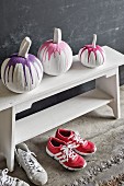 Painted pumpkins on white cloakroom bench above pairs of trainers