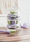 A glass jar filled with wishes written on coloured piece of paper