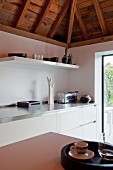 Corner of white designer kitchen with rustic roof structure