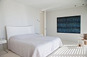 Wall decoration in shades of blue in minimalist white bedroom