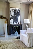 Flokati rug, white loose-covered armchair and fireplace below modern artwork in traditional interior