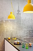 Pale grey New York skyline as background for kitchen counter below yellow pendant lamps
