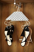 Wire coat hangers decorated with black and white polka-dot paper used to hang up lady's sandals