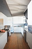 Moderne Küche mit weißen Fronten und Holzboden