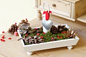 Festive table decoration in wooden dish with moss, pine cones, love-heart & stars