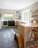 U-shaped kitchen counter and breakfast bar with solid wooden frame in kitchen with pale grey walls