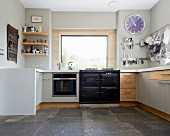 Pale grey, contemporary kitchen with U-shaped counter, integrated AGA cooker and dark grey stone floor