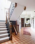 Runner on vintage chequered floor in foyer; staircase to one side with carved newel posts