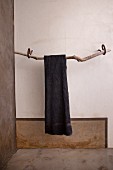Handtuchhalter aus Treibholz mit grauem Handtuch an der Wand
