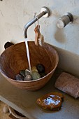 River pebbles in wooden sink on concrete washstand