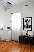 Schriftplakat über Vintage Truhe neben Fenster und einfache Küchenzeile in Altbauwohnung