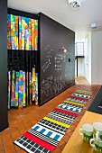 Brightly patterned rug on tiled floor and chalk drawings on wall painted with chalkboard paint