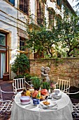 Autumnal arrangement on table and graceful antique chairs in courtyard of manor house