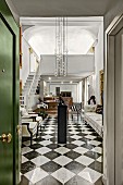 Chequered floor and modern pendant lamps in elegant foyer seen through open door