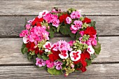 Wreath of geraniums on wooden table outside