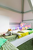 Colourful floor cushions and soft toys in seating area in child's attic bedroom