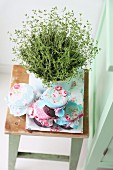 Potted thyme and home-made jam in romantically decorated jam jars on vintage stool