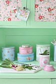 Vintage kitchen dresser with collection of romantic tins and spring onions on chopping board