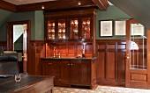 Smoking room with panelled wainscoting and glasses under spotlights in elegant, glass-fronted cabinet