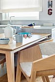 Dining table and designer, pale wood shell chairs in open-plan kitchen