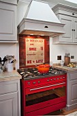 Pale grey, country-house-style fitted kitchen with red gas cooker under extractor hood