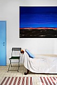 Nostalgisches Bettsofa mit Tagesdecke und Balkonstuhl vor modernem Gemälde in südländischem Ambiente
