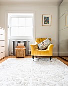 Golden-yellow armchair on white rug next to deep-set window