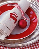 Red and white gingham ribbon, bauble and linen napkin embroidered with stag motif