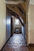 Long hallway with low ceiling and rustic stone-tiled floor