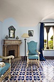 Eleganter Fliesenboden mit Ornament Muster, gepolsterte Stühle mit hellblauem Bezug vor offenem Kamin (Villa Cimbrone Hotel)