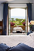 Hotel room with view of set table, park and ocean through open balcony doors (Villa Cimbrone Hotel, Italy)