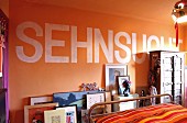 Ausschnitt eines Schlafzimmers mit Botschaft auf orangefarbener Wand