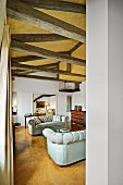 Helle Couchgarnitur im Wohnraum mit goldgelber Farbgestaltung auf Boden und Decke, rustikale Tragwerkskonstruktion
