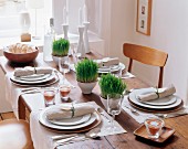 Set dining table decorated with grass, lentil-filled tealight holders and linen napkins