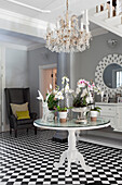 Round classic dining table with orchids and crystal chandelier with black and white chequered floor