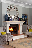 Fireplace room with wing chairs, oriental carpet and decorative mirror