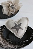 Hand-sewn heart-shaped cushion with star printed on fabric arranged in black cake tin