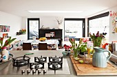 View past flowers and gas hob on island counter into dining area of houseboat