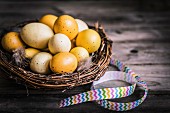 Gelb gefärbte Eier in Körbchen mit Geschenkband