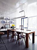 Solid wooden table in dining room with painted ceiling and grey rubber floor